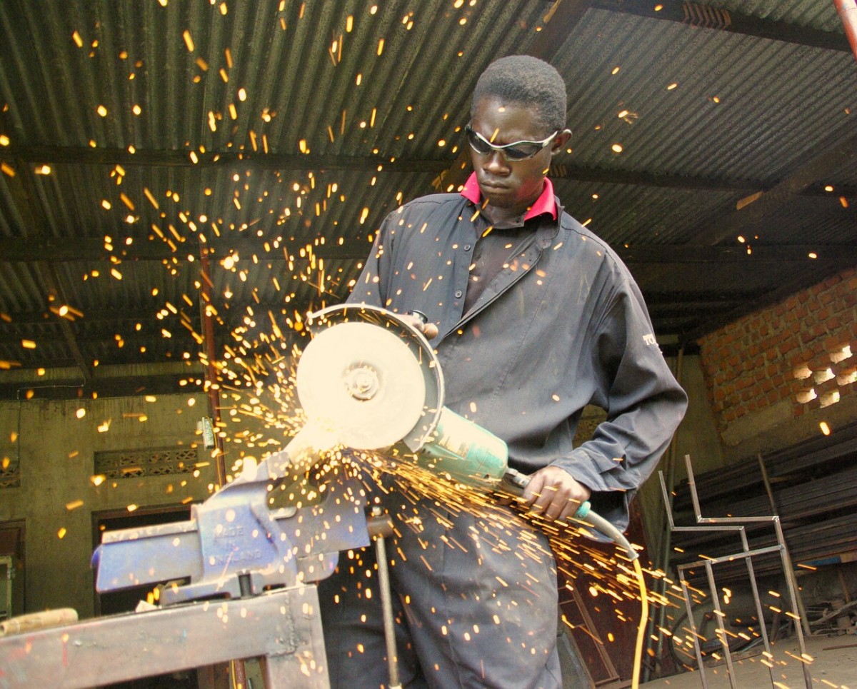 Junger Mann beim Sägen von Metall - ohne Handschuhe und ausreichende Schutzkleidung