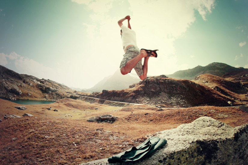 Mann macht einen Luftsprung voller Energie und Freude auf dem erreichten Gipfel